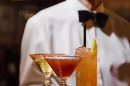 在贝博体彩app的苦艾酒餐厅，一名戴着领结的服务员展示一盘鸡尾酒.