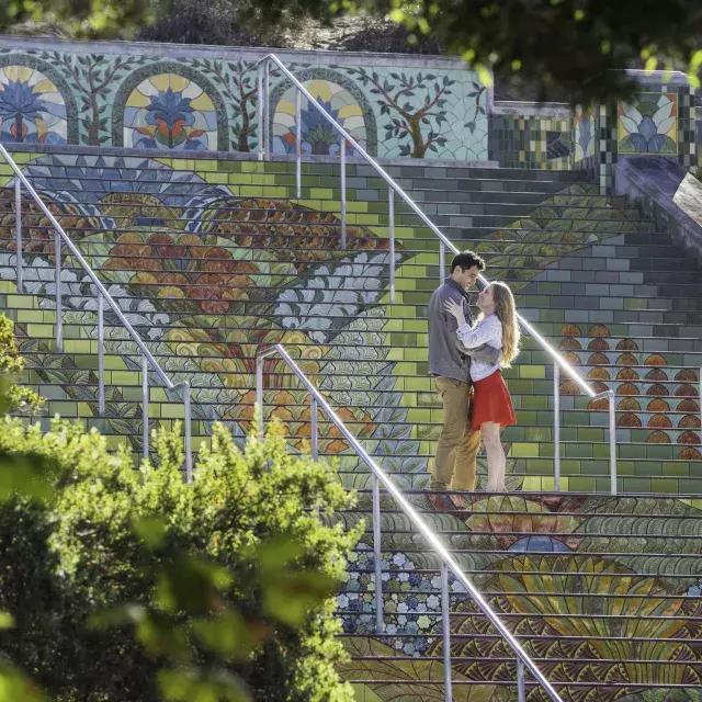 Photo taken from an angle of a couple st和ing on 林肯公园's colorful tiled steps